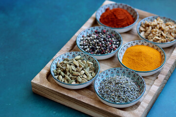 Top view arrangement with spices in bowls. Colorful picture of aromatic Indian herbs and spices on a table. Blue background with copy space. 
