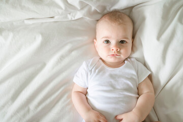 Adorable baby boy in white sunny bedroom in the morning at home