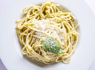 Italian spaghetti with fresh homemade pesto sauce. Eaten on a white wooden board.