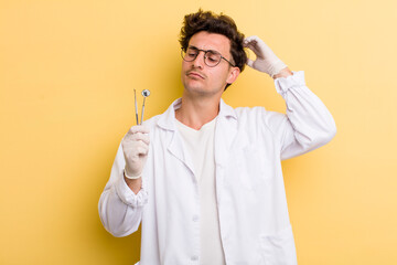 young handsome guy feeling puzzled and confused, scratching head. dentist concept