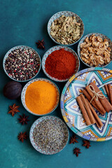 Top view arrangement with spices in bowls. Colorful picture of aromatic Indian herbs and spices on a table. Blue background with copy space. 