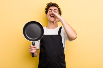 young handsome guy feeling happy,giving a big shout out with hands next to mouth. chef with a pan concept