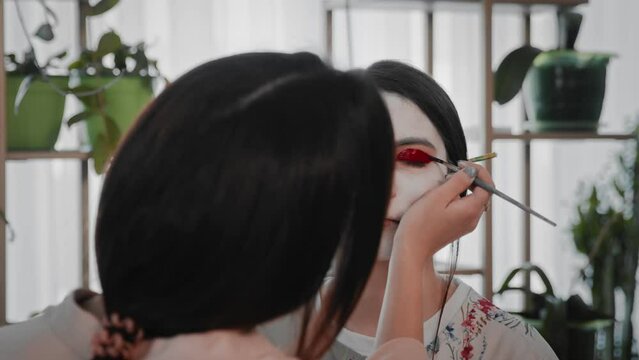 A young woman creates the image of a geisha for a girl. Makeup. Creating an image for an event