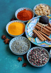 Top view arrangement with spices in bowls. Colorful picture of aromatic Indian herbs and spices on a table. Blue background with copy space. 
