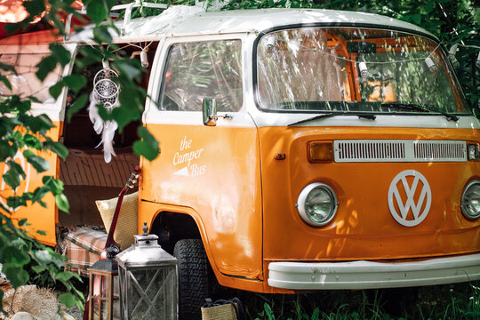 MOSCOW, RUSSIA, - JUNE 7, 2022: Classic serfer Orange Volkswagen Camper, Van, trailer parked in green forest. Vacation in mobile home, picnic near the camper trailer.