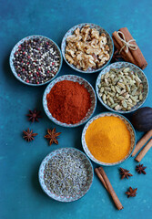 Top view arrangement with spices in bowls. Colorful picture of aromatic Indian herbs and spices on a table. Blue background with copy space. 