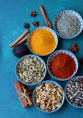 Top view arrangement with spices in bowls. Colorful picture of aromatic Indian herbs and spices on a table. Blue background with copy space. 