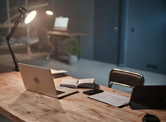 interior of a night office with a desk and an open laptop .