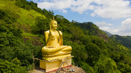 A statue of the golden Buddha in a mountain Buddhist temple. Aluvihara Rock Temple, Matale, Central...