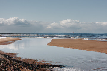 sea beach with white sand and blue water before storm. waves with white heads