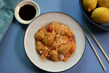 Top view of sweet and sour chinese chicken dish on blue background