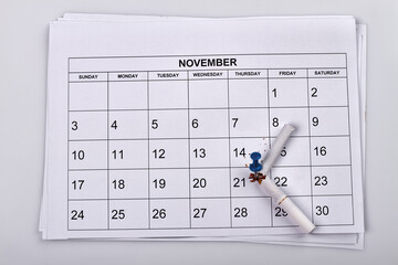 Broken cigarette with push pin on the month calendar. November calendar on white background.