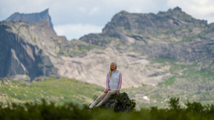 Portrait of a girl against the background of mountains. Summer day