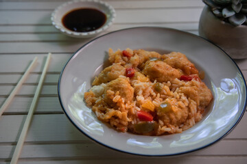 Side view of sweet and sour chinese chicken dish on blue background