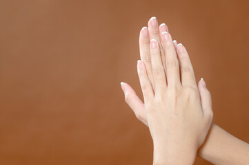 Close up young woman hand is applying cream over brown background , beauty skin care concept