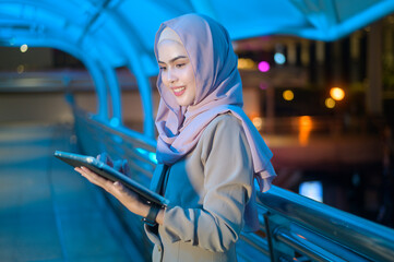 A young Muslim Businesswoman is using tablet computer in modern City at night , Business technology lifestyle concept