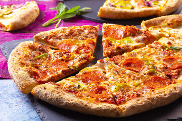 Chorizo pizza baked with tomatoes and mozzarella on slate board.