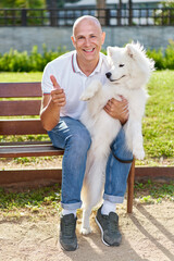 Samoyed dog with her man owner at the park playing together