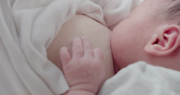 Asian mother breastfeeding her newborn baby in a nursery at home, newborn baby suckling milk from breast, family, motherhood, parenthood, childhood, Healthcare, love, relationship concept