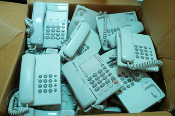 Many piles of broken or unused landline telephone are thrown in cardboard boxes, Communication...