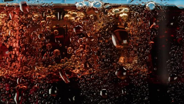 Cold lemonade in glass close-up. Coca cola with ice macro shooting texture. Refreshing cocktail.