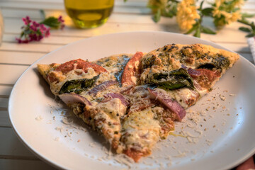 Side view and closeup of vegetarian pesto pizza on white plate.