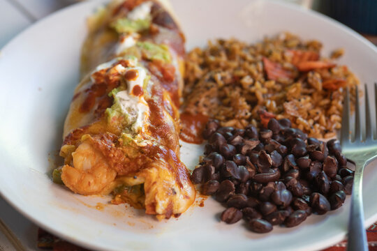 Side and closeup View of shrimp enchiladas on white plate.