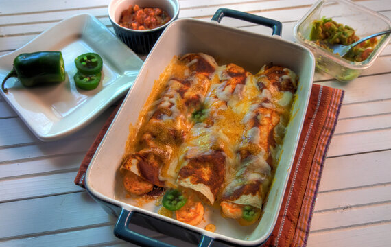 Top View of shrimp enchiladas on white natural wood surface