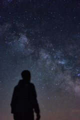 Persona de espaldas observando el cielo estrellado y la Vía Láctea