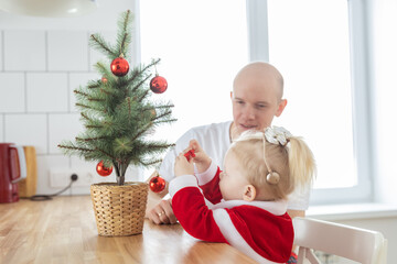 Father with toddler daughter with cochlear implants having fun in christmas living room - inclusion and innovating treatment for deafness with cochlear implant surgery