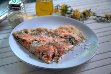 Side view of smoked salmon pizza on white natural wood table