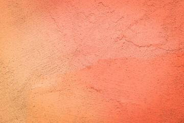Rough concrete wall painted in orange with brush strokes