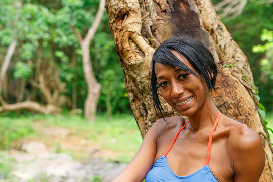 A beautiful Dominican girl sits in nature near a tree. Portrait of a Dominican.