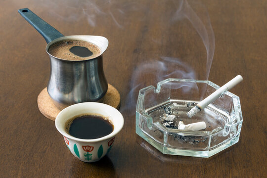 Traditional Lebanese coffee pot and cup with ashtray and cigarette on a wooden table