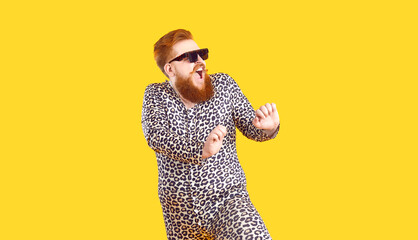 Crazy plus size man in funny pajamas dancing and having fun in fashion studio. Happy bearded fat...