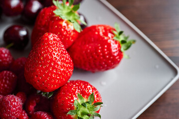 A full plate of juicy, bright pink freshly washed strawberries. Wet strawberries. A plate of summer vitamins. Space for text.