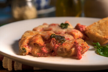 Side view of stuffed rigatoni on white plate