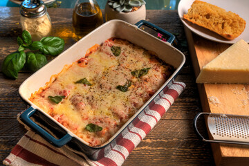 Top view of stuffed rigatoni in baking dish on natural wood table top.