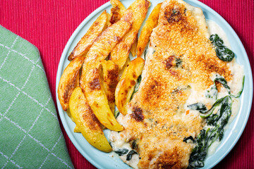 Hake fish prepared with spinach cream and French fries served for dinner