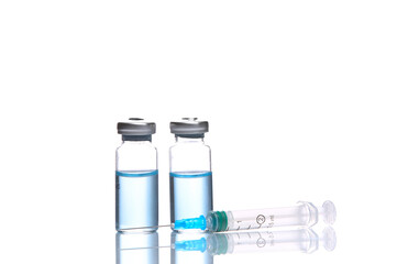 Vaccine bottles with blue liquid and syringe isolated on white background with reflection