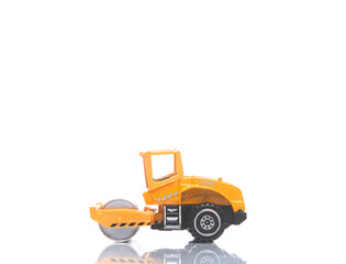 Toy model of asphalt paver on white background with reflection