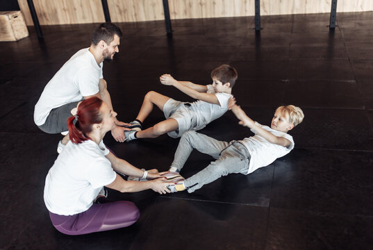 Healthy Family Concept. Mom And Dad Trainers Train Their Teenage Sons In The Gym