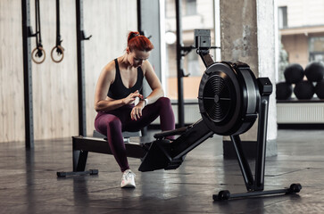 Fototapeta na wymiar Athletic woman using smart watch in modern gym. Healthy lifestyle