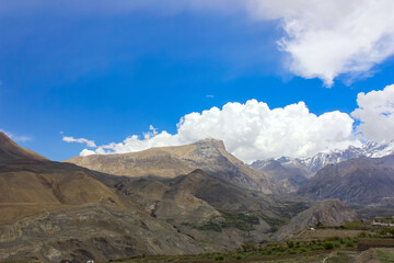 Brown mountains against the blue sky with white clouds