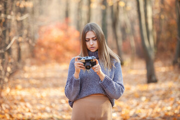 Young caucasian woman with retro camera in autumn forest