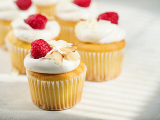 Close-up. Muffins with whipped cream, raspberries and almonds. Isolated on white background. There are no people in the photo. Sweet food, calories. Banquet, picnic, holiday, birthday.
