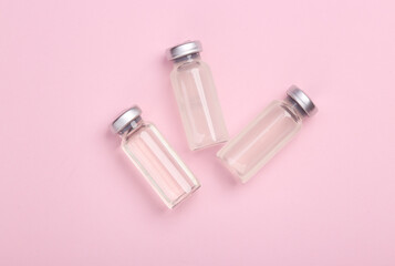 Medical glass jars of vaccine on a pink background. Top view. Flat lay