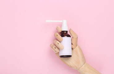 Wooden hand holding Throat spray mockup with blank white label for branding or text on pink...