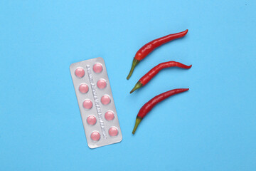 Blister of pills with red chili peppers on a blue background. Medicine concept