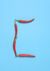 Letter C made from red chilli peppers on blue background